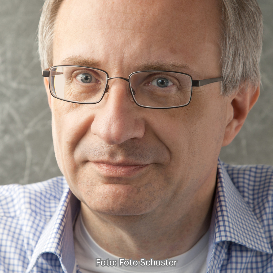 Das Foto zeigt den österreichischen Kommunikationswissenschaftler Josef Seethaler. Er schaut direkt in die Kamera. Er trägt ein blau-weiß kariertes Hemd und eckige Brillen mit dünnem Rand.