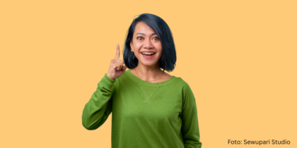 Eine Frau hebt einen Zeigefinger hoch und lächelt. Sie hat etwas verstanden.