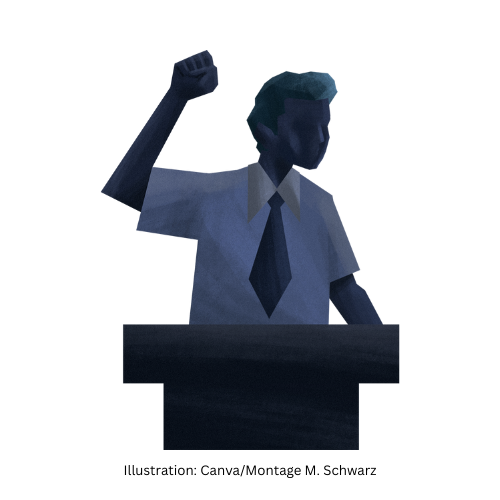 ein Mann an einem Rednerpult, der energisch die geballte Hand in die Höhe streckt